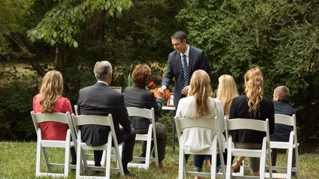 Outdoor funeral memorial ceremony with family gathering.
